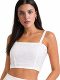 A woman modeling a white cropped camisole top with thin straps and a square neckline against a plain white background.